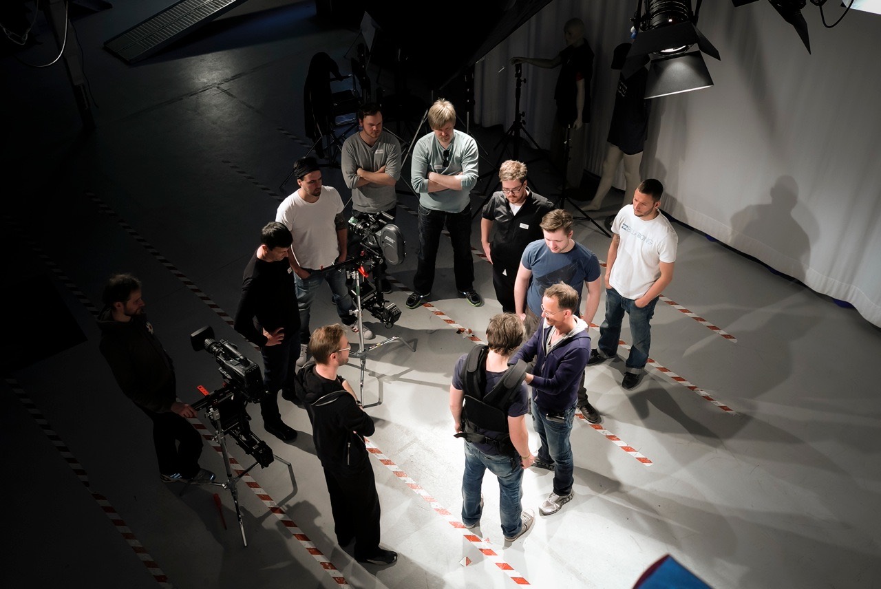A film crew gathered around a Steadicam rig on a studio floor