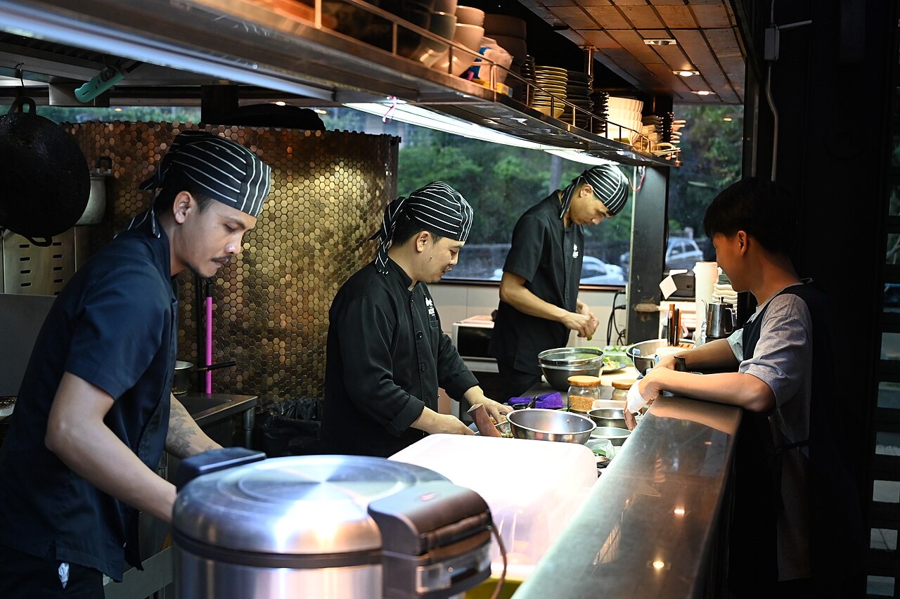 Kitchen staff working the line behind the counter of a busy restaurant