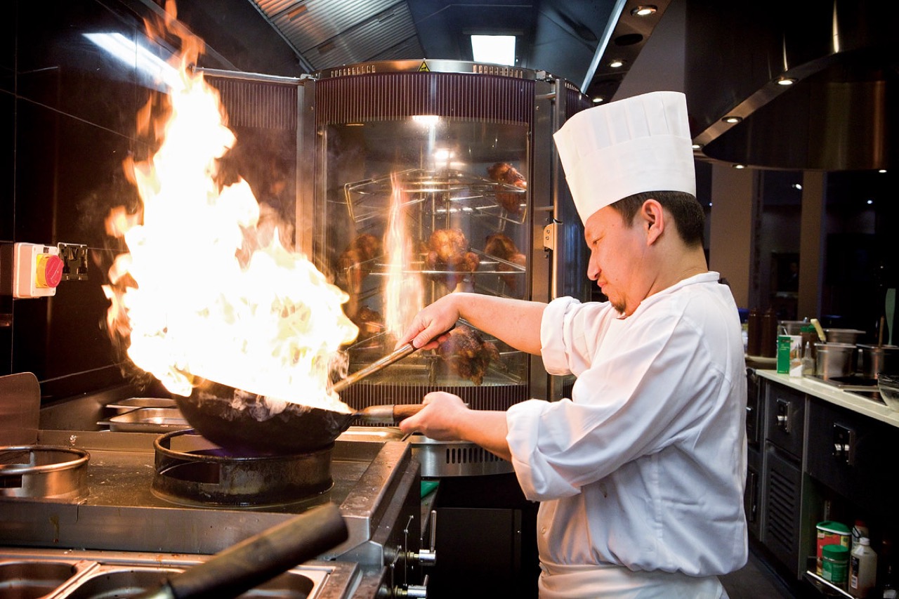 A chef tossing a flaming wok in a professional kitchen