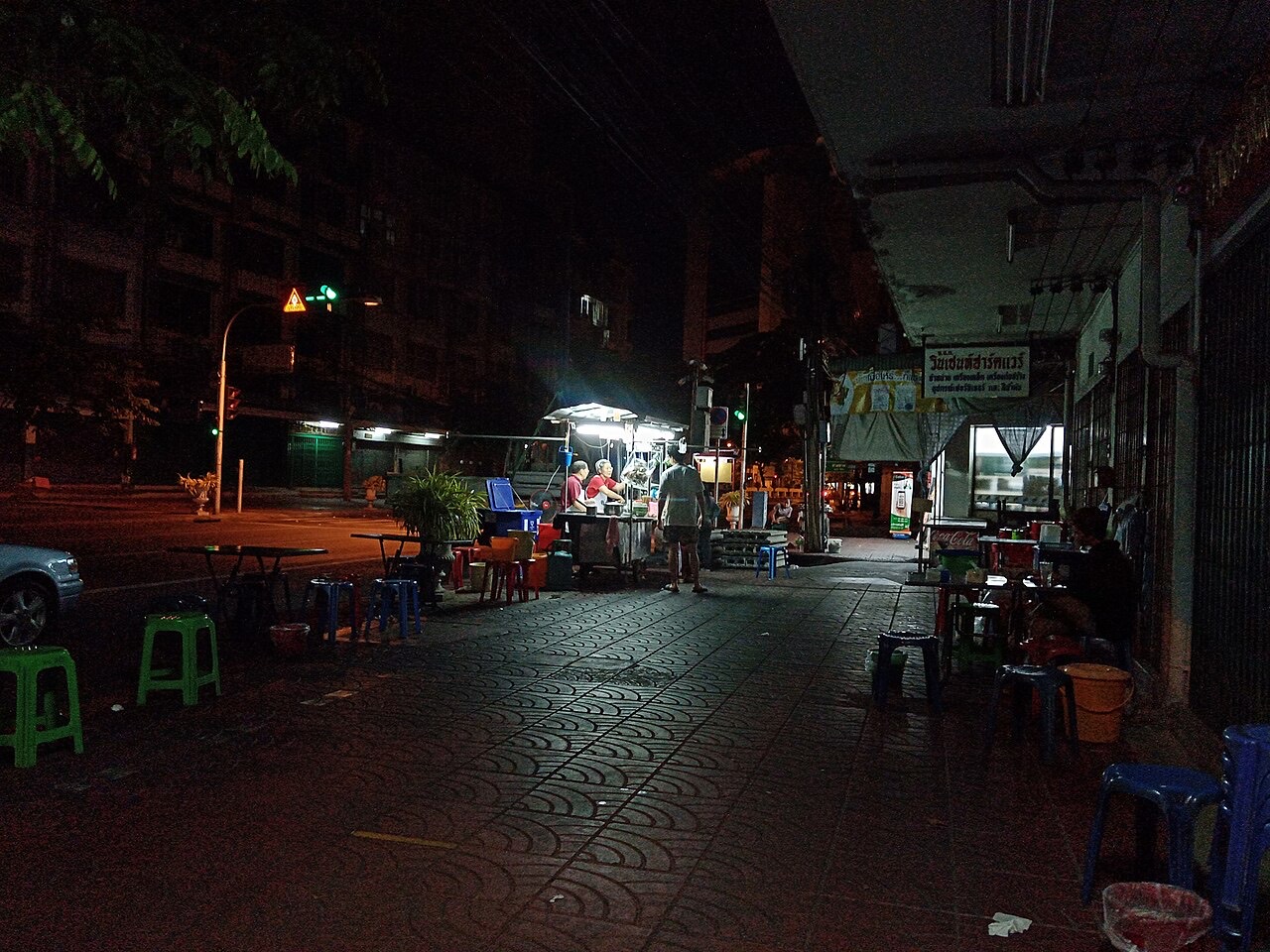 A lone street food stall glowing at night on a Bangkok street